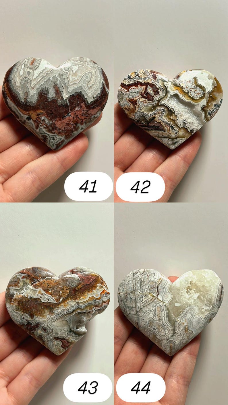 May include: Four heart-shaped stones with unique patterns and colors. The stones are held in a hand and numbered 41, 42, 43, and 44. The stones have a variety of colors, including red, brown, white, and gray. The stones are likely decorative items.