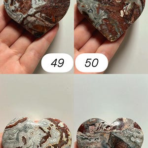 May include: Four heart-shaped stones with unique patterns and colors. The stones are held in hands and numbered 49, 50, 51, and 52. The stones have a mix of red, brown, gray, and white colors, with intricate veining and patterns throughout.