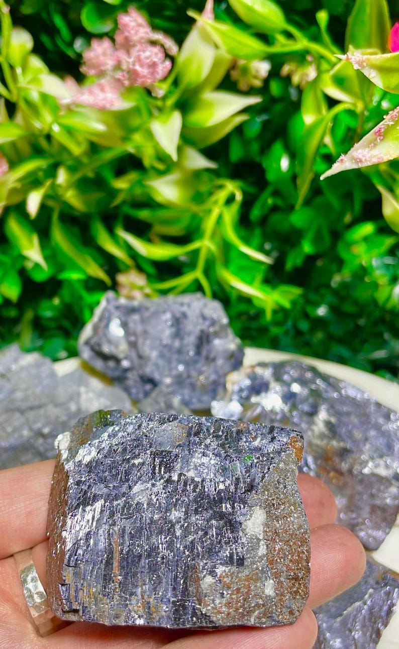 Puede incluir: Un gran cristal met&aacute;lico gris oscuro con una superficie rugosa y texturizada. El cristal tiene un brillo plateado y una forma irregular.