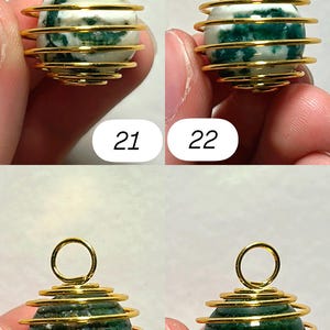 May include: Four gemstone pendants with gold-colored wire wrapping. The gemstones are spherical, with variations in color and pattern. Two pendants have white and green stones, while the other two are dark green. Each pendant has a loop at the top. Numbers 21, 22, 23, and 24 are visible.