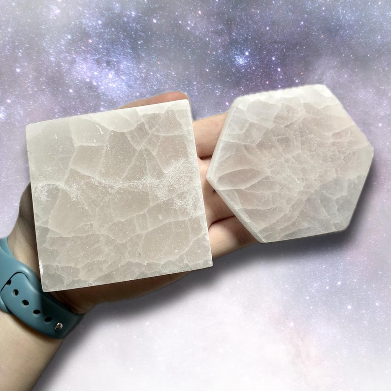 K&ouml;nnte beinhalten: Zwei hellfarbene, strukturierte Untersetzer aus Stein. Einer ist quadratisch, der andere sechseckig. Die Untersetzer werden vor einem Hintergrund mit einem sternenartigen, galaxieartigen Design gehalten. Die Untersetzer sind aus hellfarbenem Stein.