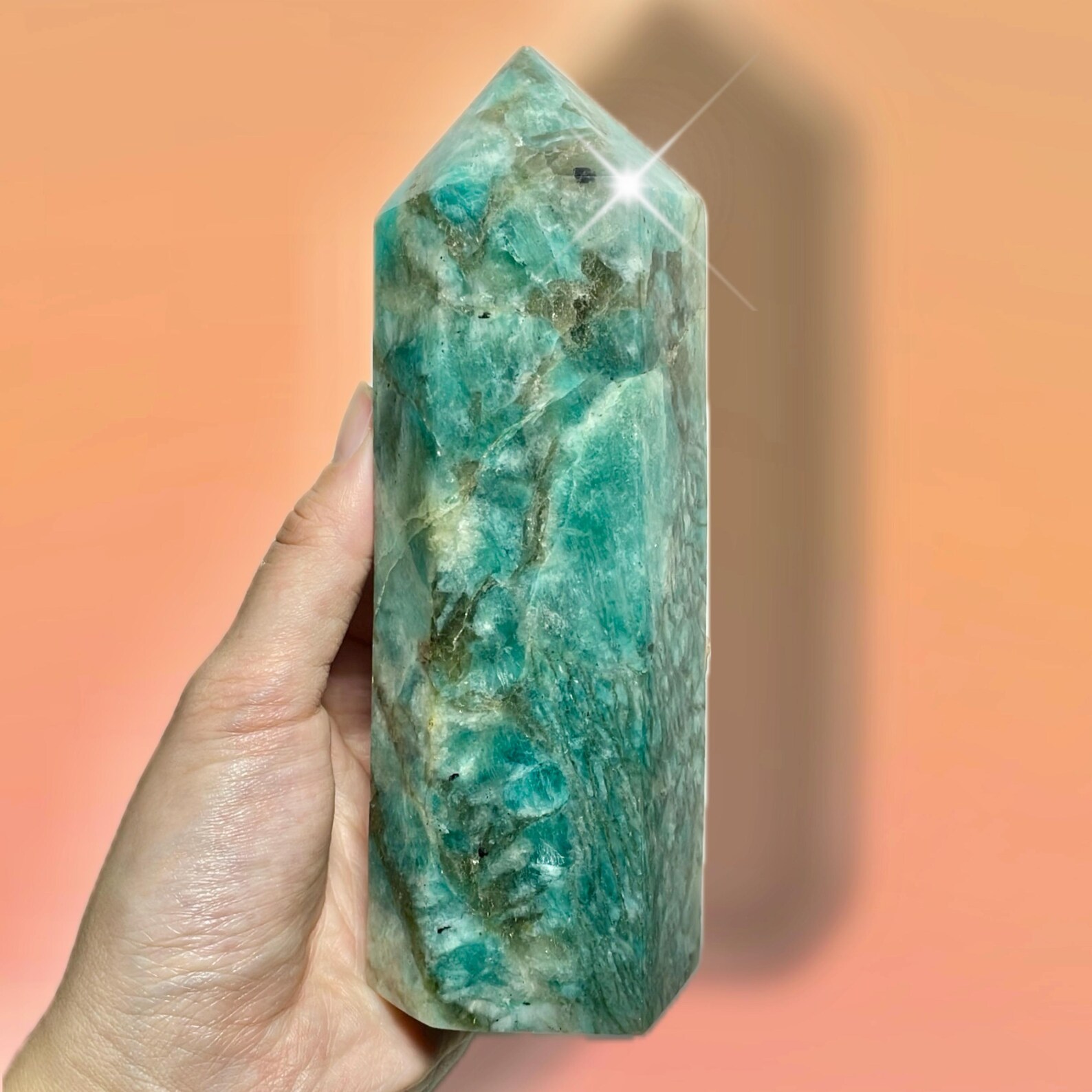 Amazonite crystal point in hand with soft teal and green swirls, used for Virgo healing