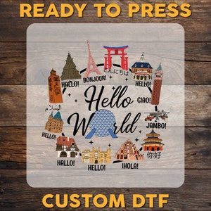May include: A clear, rectangular sticker with a colorful illustration of landmarks from around the world. The landmarks are arranged in a circle around a blue and white globe. The text "Hello World" is written in a large, bold font above the globe. The text "Ready to Press" is written in a large, bold font at the top of the sticker. The text "Custom DTF" is written in a large, bold font at the bottom of the sticker.