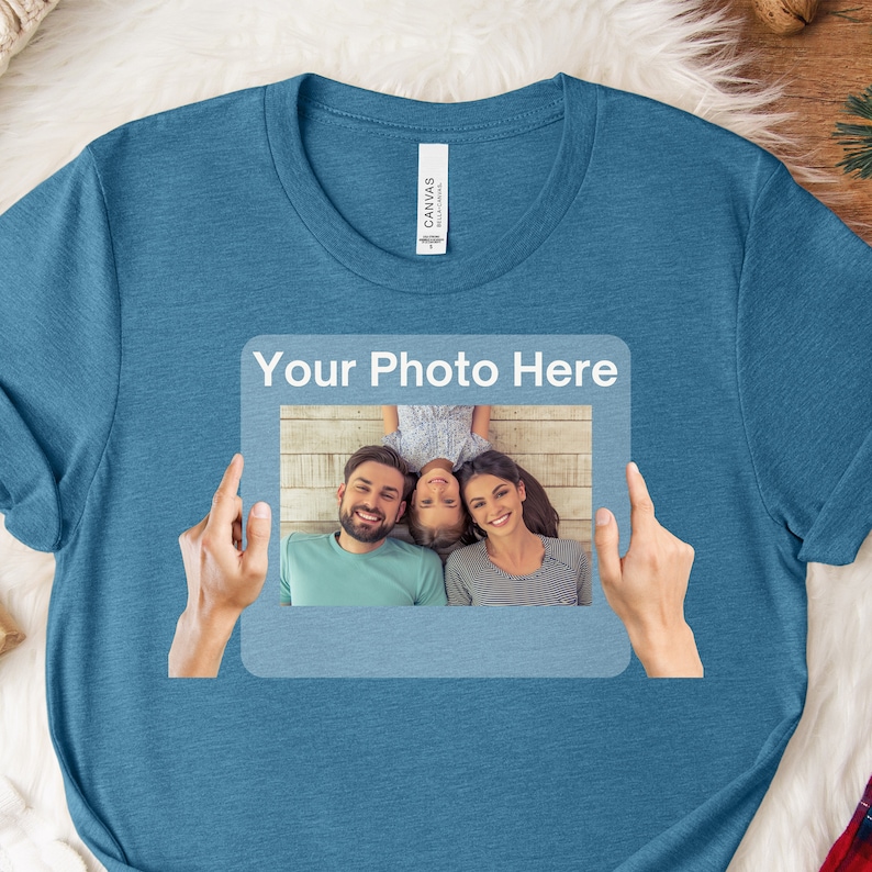 May include: A blue t-shirt with a white frame that says "Your Photo Here" and a photo of a family of three inside the frame.