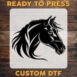May include: Black horse head silhouette design on a white background. The image includes the text "READY TO PRESS" at the top and "CUSTOM DTF" at the bottom. The design is set against a wooden background.