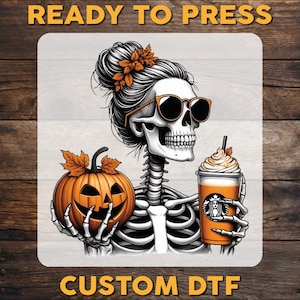 May include: A Halloween-themed graphic featuring a skeleton with sunglasses and a bun, holding a pumpkin and a pumpkin spice latte. The image has the text "READY TO PRESS" and "CUSTOM DTF". The skeleton is wearing sunglasses and has a floral hair accessory.