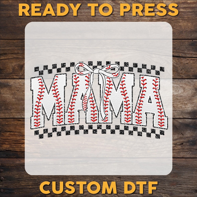 May include: A white iron-on transfer design with the word "MAMA" in black letters with a baseball stitch pattern. A red bow is above the word. The design is on a checkered background.