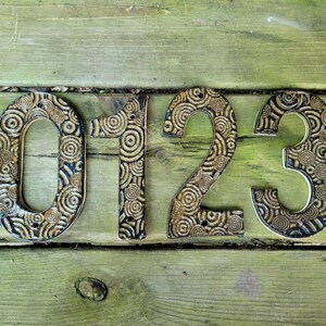 May include: Ceramic house numbers 0123 with a swirling pattern in black and gold.