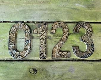 May include: Ceramic house numbers 0123 with a swirling pattern in black and gold.