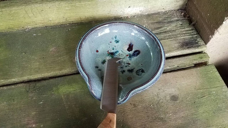 Op de afbeelding: Een blauwe keramische botervloot met een mes erin. De vloot heeft een gespikkeld glazuur met blauwe, groene en rode accenten.