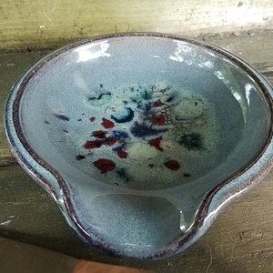 Op de afbeelding: Een blauwe keramische lepelsteun met een gespikkeld glazuur in tinten blauw, wit en rood.