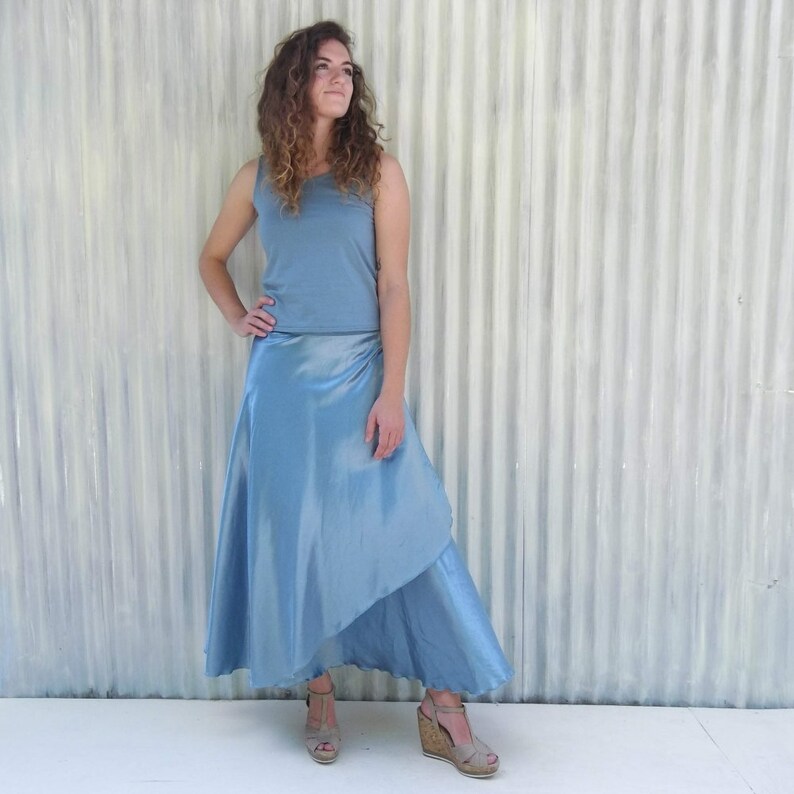 Puede incluir: Una falda de envoltura azul claro con un dise&ntilde;o asim&eacute;trico fluido. La falda est&aacute; hecha de una tela sedosa y brillante y tiene un estilo simple y elegante.