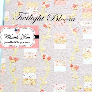 Peut inclure: Patron de quilt pour une courtepointe "Twilight Bloom". Le motif présente un fond gris clair avec des vignes jaunes et des fleurs roses. Le motif est conçu pour un rouleau de tissu jelly. Le texte "Fig Tree & Co." est dans le coin inférieur droit.