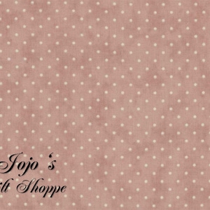May include: A pink fabric with a white polka dot pattern. The fabric has the text "Jojo's Quilt Shoppe" in black lettering.
