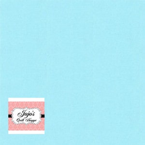Puede incluir: Un fondo de tela azul claro liso. En la esquina inferior izquierda hay un logotipo con el texto "Jojo's Quilt Shoppe" en un marco decorativo con un estampado floral rosa.