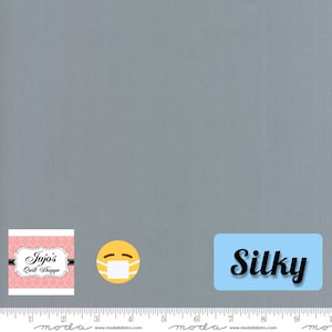 Puede incluir: Una muestra de tela azul claro con el texto "Jojo's Quilt Shoppe" y la palabra "Silky" en un cuadro azul. También se ve una cara sonriente amarilla con una mascarilla blanca.