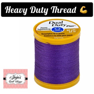 May include: A spool of purple Coats Dual Duty Plus thread for topstitching jeans. The spool is labeled with the text "Dual Duty Plus", "Jeans Topstitching", "Surpiq&ucirc;re fil &agrave; jeans", "Costura a la vista para jeans", "60 yds. 54 m", and "Mexico".