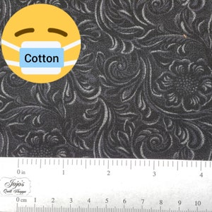 Puede incluir: Tela de algodón negra con un patrón de remolino blanco. La tela se mide con una regla en pulgadas. La palabra "Cotton" está escrita en una máscara azul que lleva un emoji amarillo.