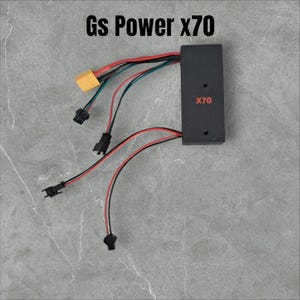 Puede incluir: Un componente electrónico negro con la inscripción "Gs Power X70", con cables y conectores rojos y negros. El componente tiene el texto "X70" en rojo. También se ve un conector amarillo.