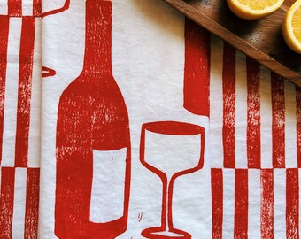 May include: Red and white striped kitchen towel with a red wine bottle and wine glass design.