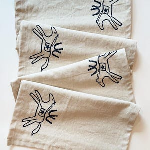 May include: Set of four beige linen napkins with a black and white horse design printed on each napkin.