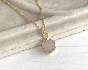 May include: A delicate gold chain necklace with a small, round, light purple gemstone pendant.