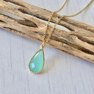 Puede incluir: Un delicado collar de cadena de oro con un colgante en forma de l&aacute;grima que presenta una piedra preciosa verde claro engastada en un bisel de oro.