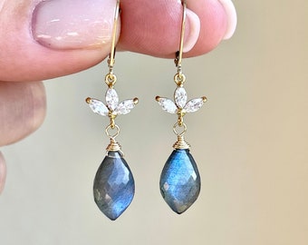 May include: Gold dangle earrings with a teardrop-shaped blue labradorite gemstone and a cluster of clear cubic zirconia stones.