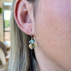 May include: Silver dangle earrings with a light green gemstone and smaller blue gemstones.