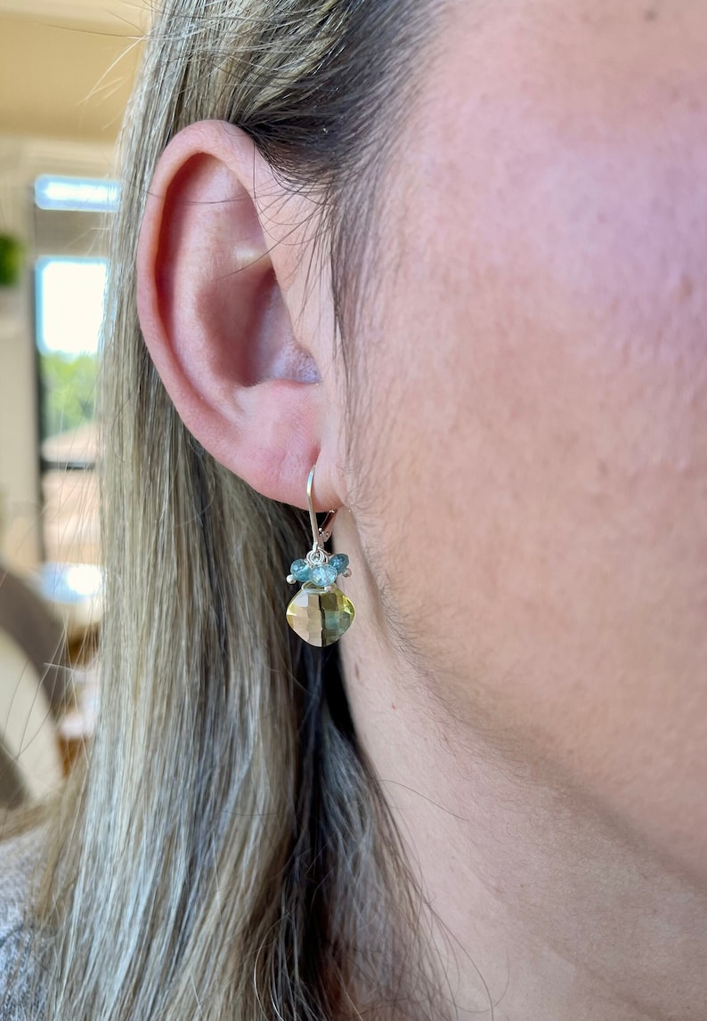 May include: Silver dangle earrings with a light green gemstone and smaller blue gemstones.