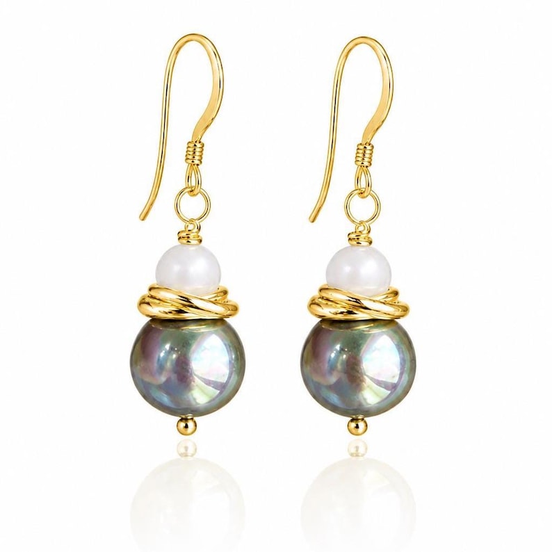May include: A pair of gold-colored drop earrings. Each earring features a large, iridescent, dark gray pearl, a smaller white pearl, and gold-colored wire detailing. The earrings have a gold-colored hook closure.