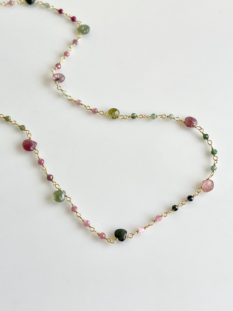Pode incluir: Um colar de corrente de ouro com pedras preciosas rosa, verde e preta. O colar &eacute; feito de pequenas contas delicadas e &eacute; perfeito para o uso di&aacute;rio.