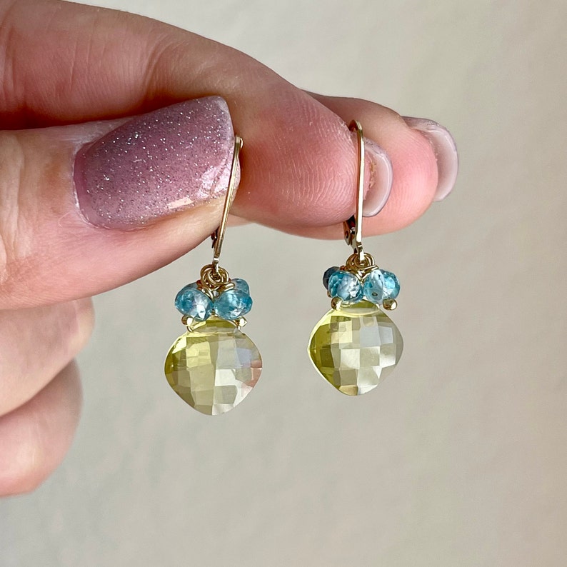May include: Gold earrings with a light yellow faceted gemstone and blue gemstone accents.