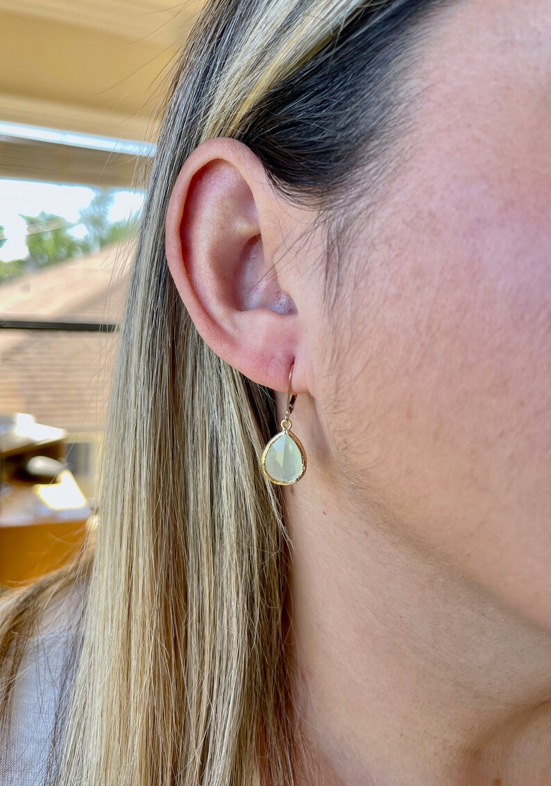 Puede incluir: Pendientes de gota de oro con una piedra preciosa verde claro.