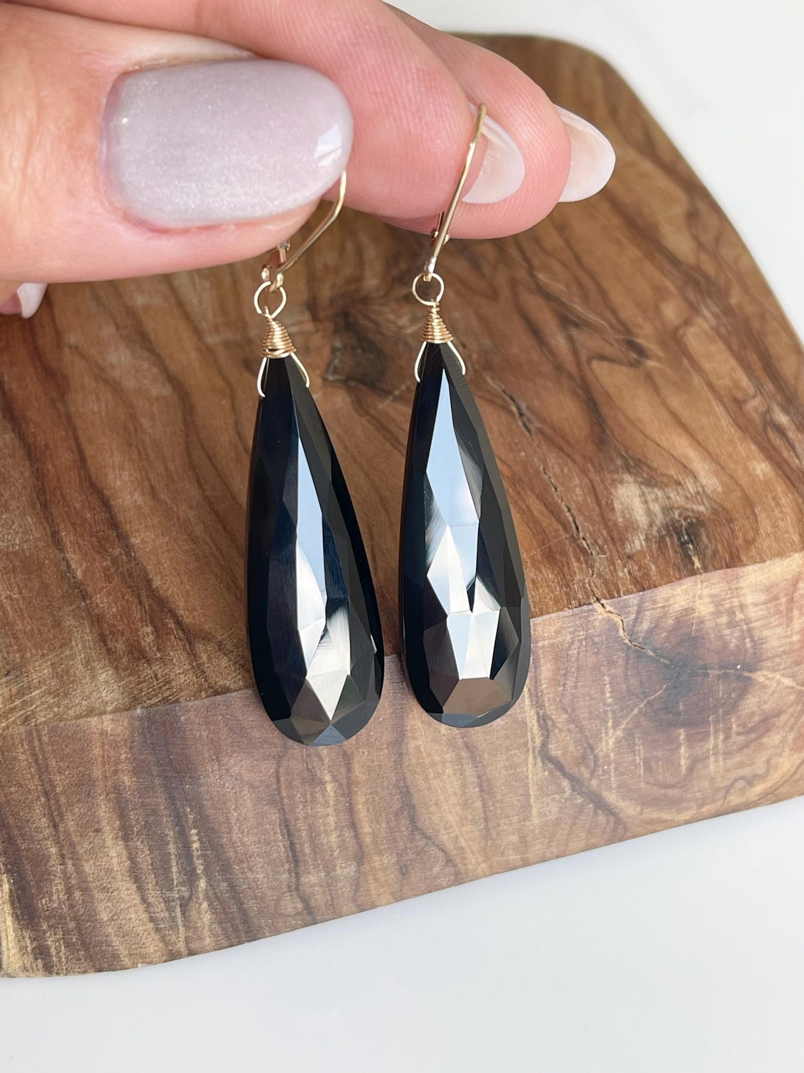 Black onyx and gold earrings displayed on wooden surface for contrast and detail