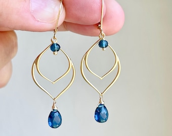 May include: Gold earrings with a double teardrop design and blue gemstone accents.