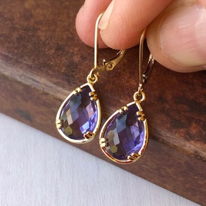 May include: A pair of gold dangle earrings with purple teardrop-shaped crystals.