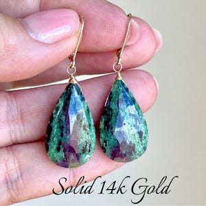 May include: A pair of teardrop-shaped earrings with green and black gemstone drops, set in solid 14k gold.