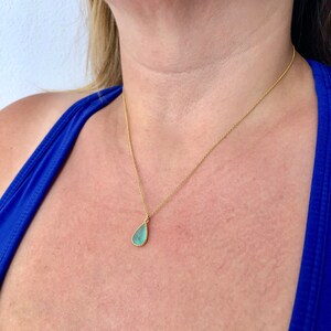 Puede incluir: Un collar de cadena de oro con un colgante en forma de l&aacute;grima con una piedra preciosa azul claro.