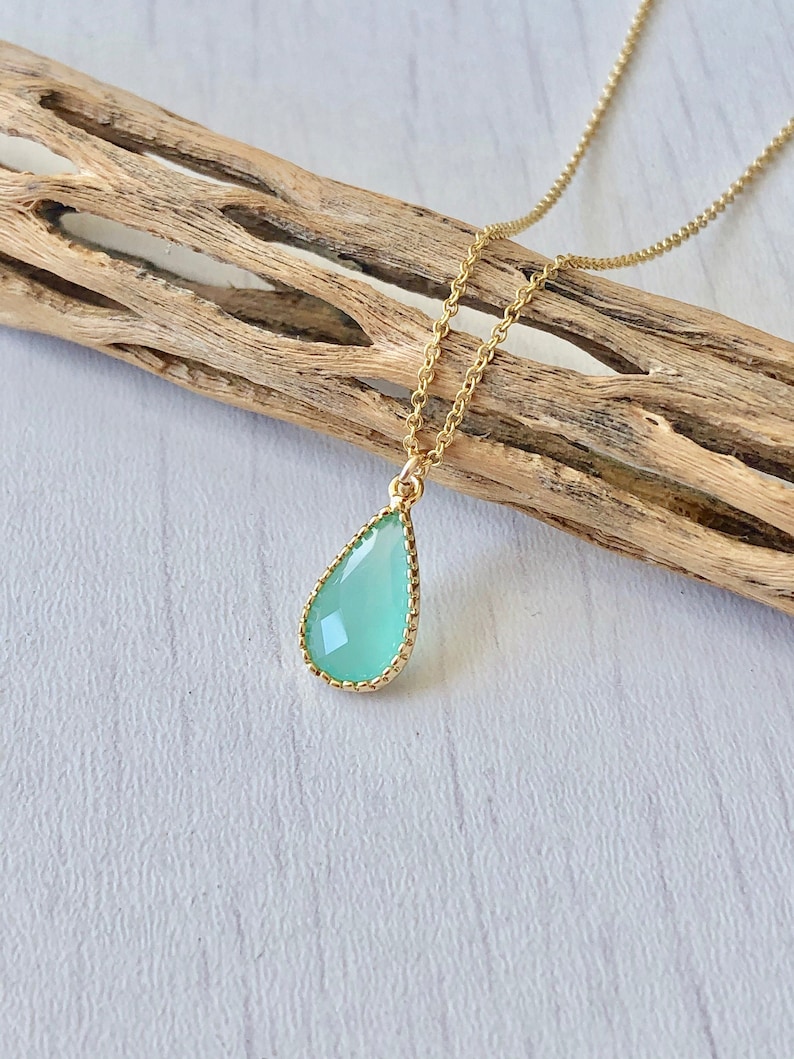 Puede incluir: Un delicado collar de cadena de oro con un colgante en forma de l&aacute;grima que presenta una piedra preciosa verde claro engastada en un bisel de oro.