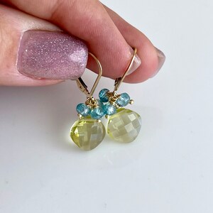 May include: Gold earrings with a light yellow faceted gemstone and blue gemstone accents.