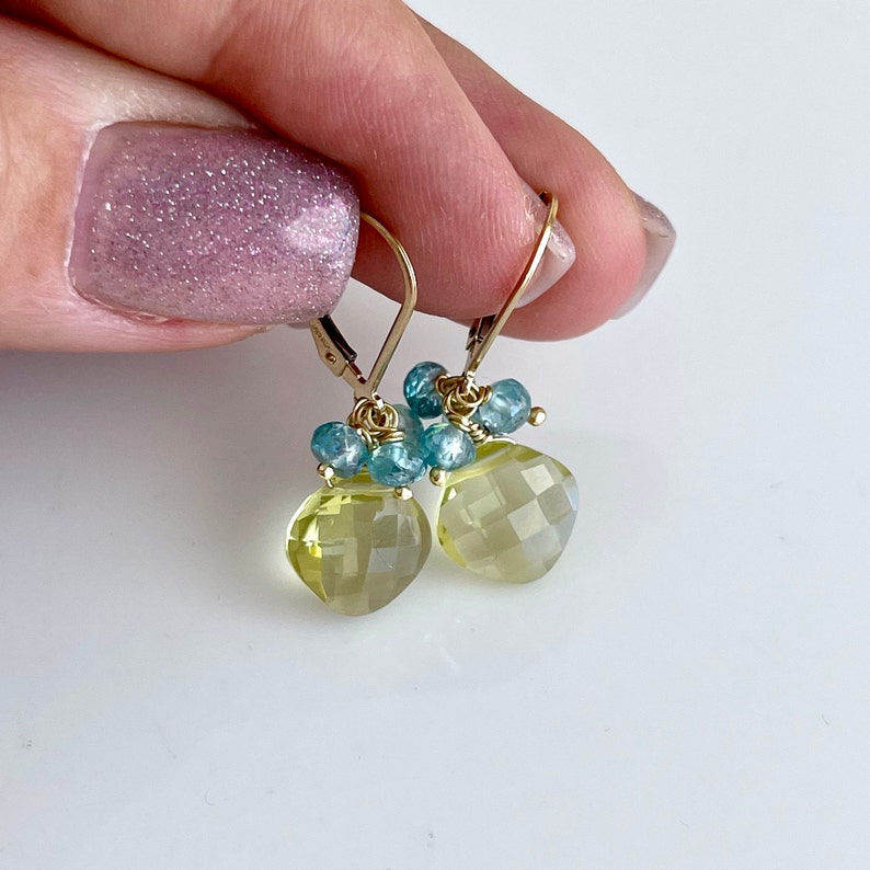 May include: Gold earrings with a light yellow faceted gemstone and blue gemstone accents.