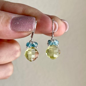 May include: A pair of silver dangle earrings with a light yellow gemstone and blue accents.