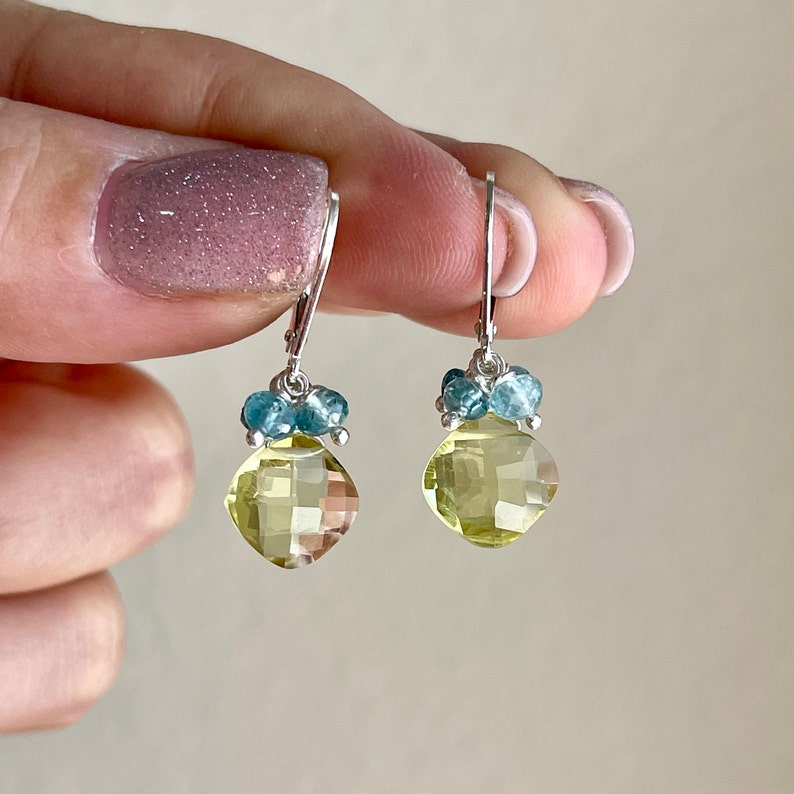 May include: A pair of silver dangle earrings with a light yellow gemstone and blue accents.