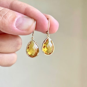 May include: A pair of gold teardrop earrings with faceted amber-colored stones.