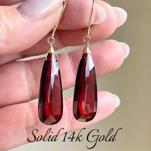 May include: A pair of dangle earrings with teardrop-shaped red gemstones and solid 14k gold wire.