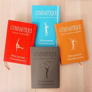 Peut inclure: Quatre carnets de gymnastique de couleurs rouge, bleu, orange et gris. Chaque carnet porte le mot "GYMNASTIQUE" et une silhouette de gymnaste. On peut lire "Mon journal d'entraînement" sur chaque carnet.