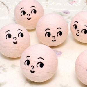 May include: Six pink foam balls with painted black faces. Each ball has a different facial expression.