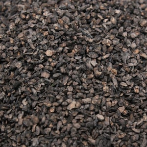 May include: A close-up of a pile of small, dark brown, irregularly shaped, and rough-textured pieces of dried fruit.