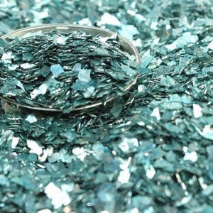 May include: A close-up of teal blue iridescent glitter, perfect for crafting and adding sparkle to projects.